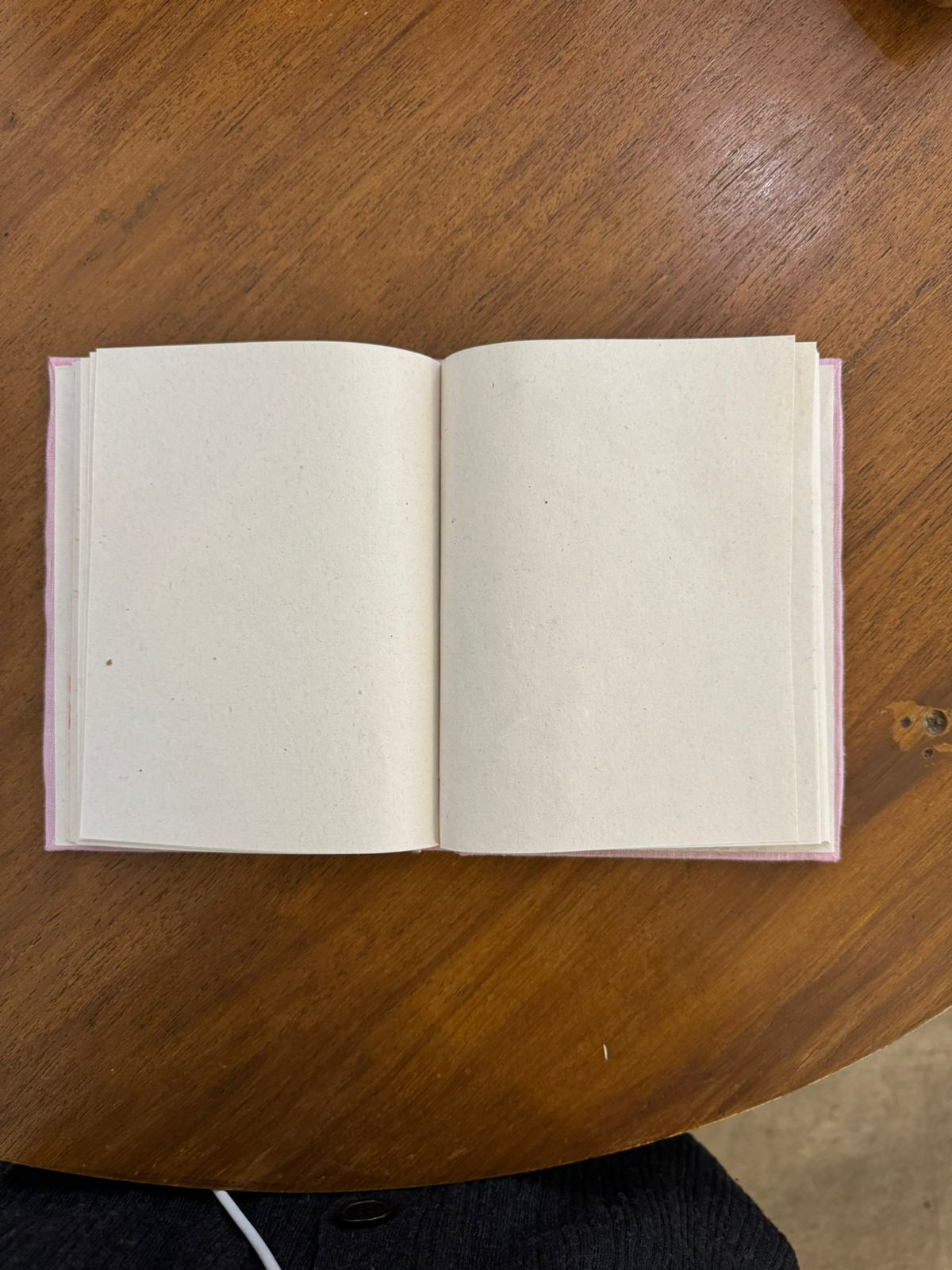 White diary with handmade sheets placed against a wooden background.