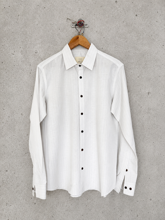 White striped shirt with black buttons on a hanger against a gray concrete wall