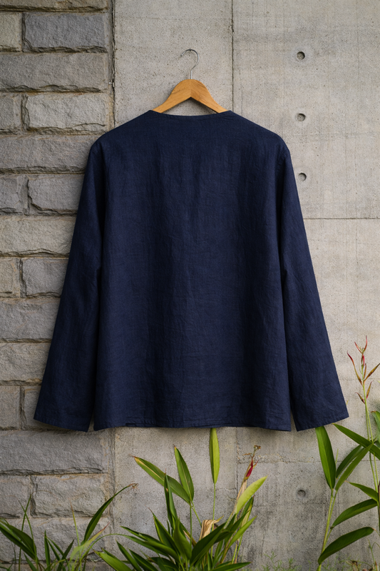 Back of blue collarless linen shirt displayed against a grey wall