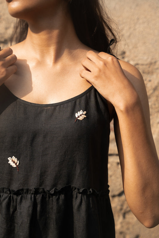 Close-up of hand-embroidered leaves on black linen dress with adjustable knot straps