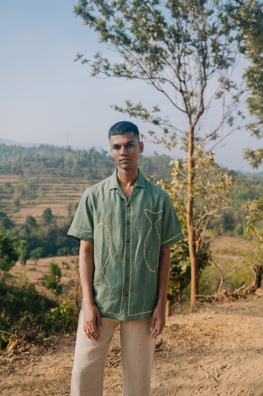 Front detail of Gopi Gopi wearing a green linen shirt with hand-embroidered fishes