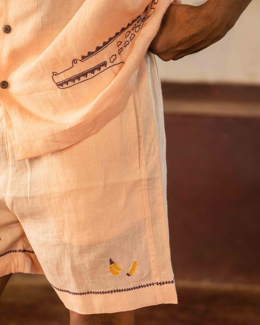 Close up view of peach linen shorts with hand-embroidered bananas.