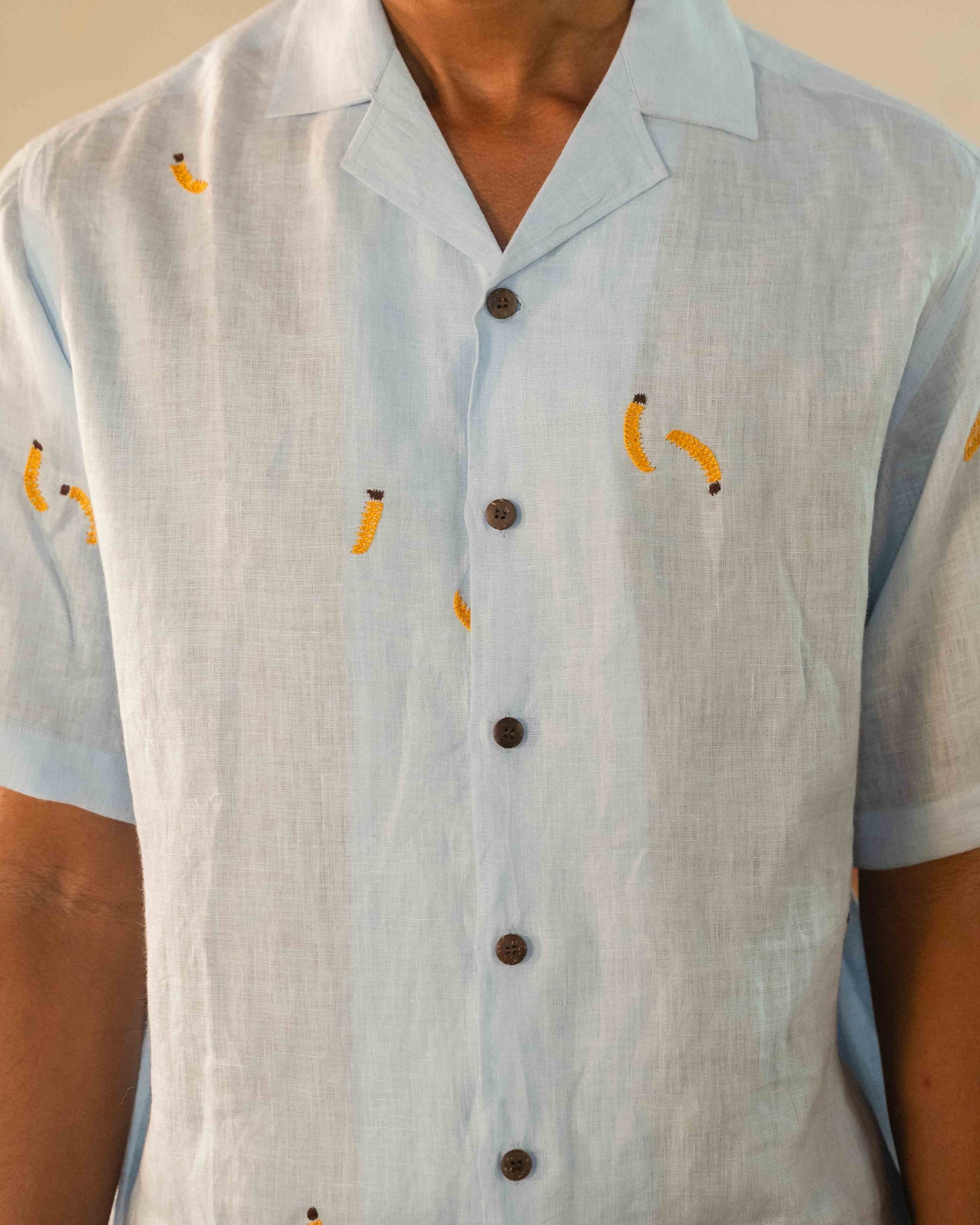 Close up of our model wearing a linen half-sleeves shirt with hand-embroidered bananas