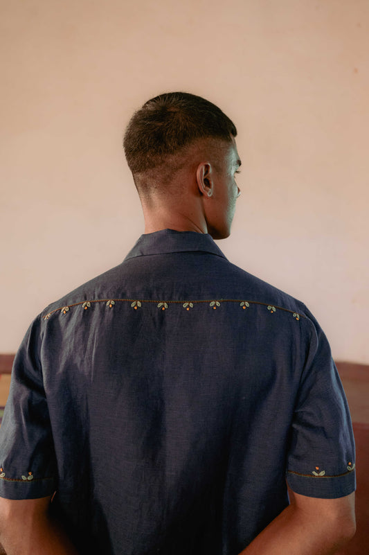 Back of the hand-embroidered navy blue linen shirt. Small flowers and buds are embroidered in one horizontal line at the shoulder divide