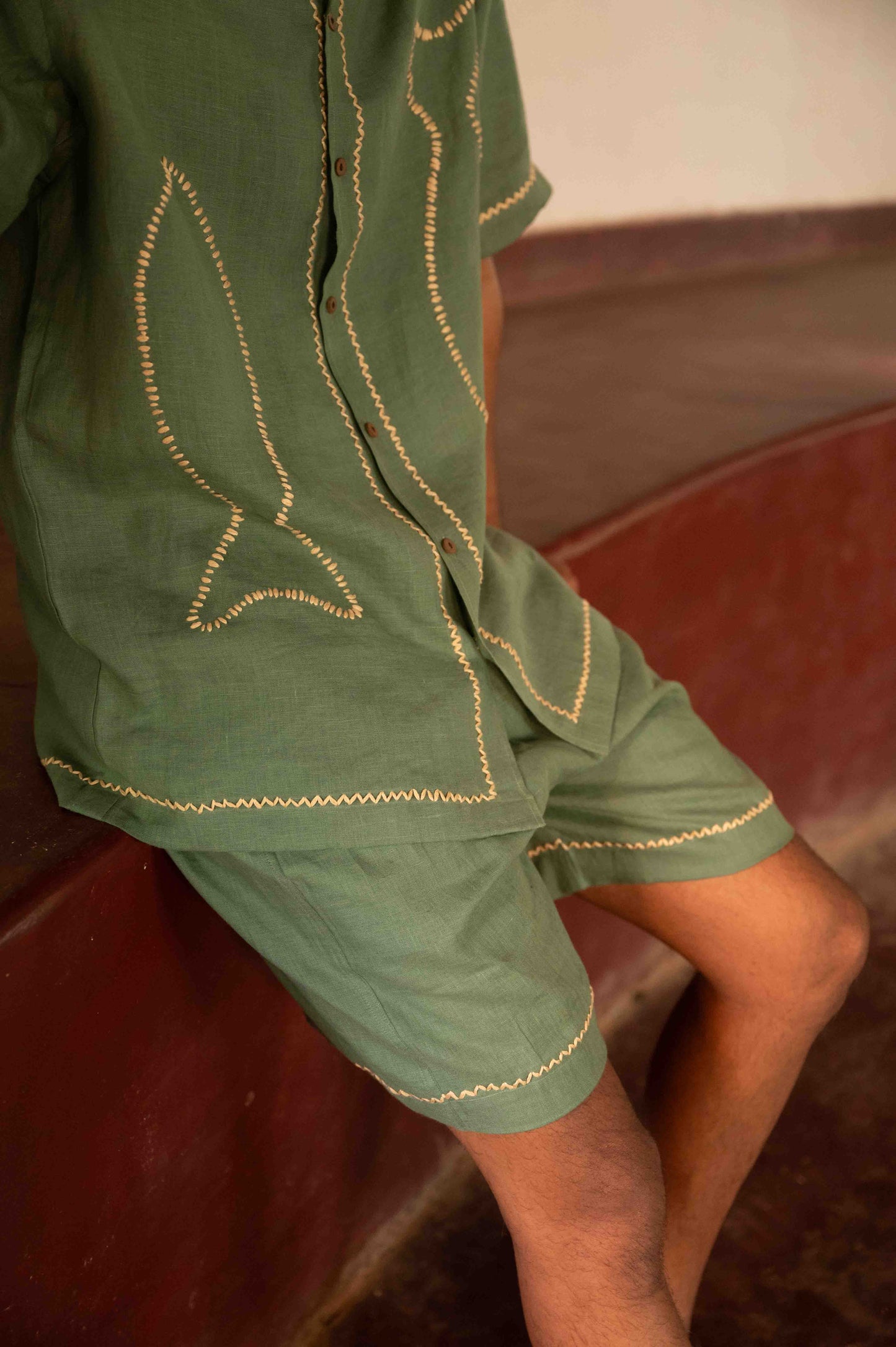 Side view of green linen shorts with hand embroidered edges
