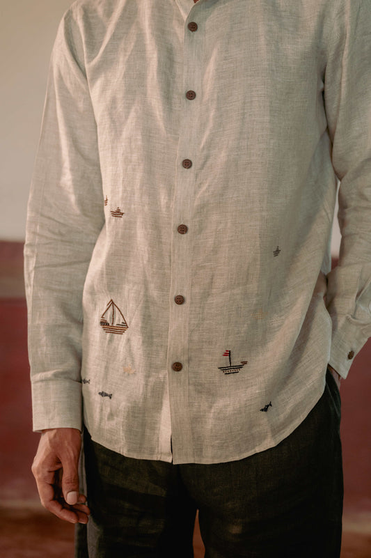 Detail of a full sleeved linen shirt with hand-embroidered boats and fishes