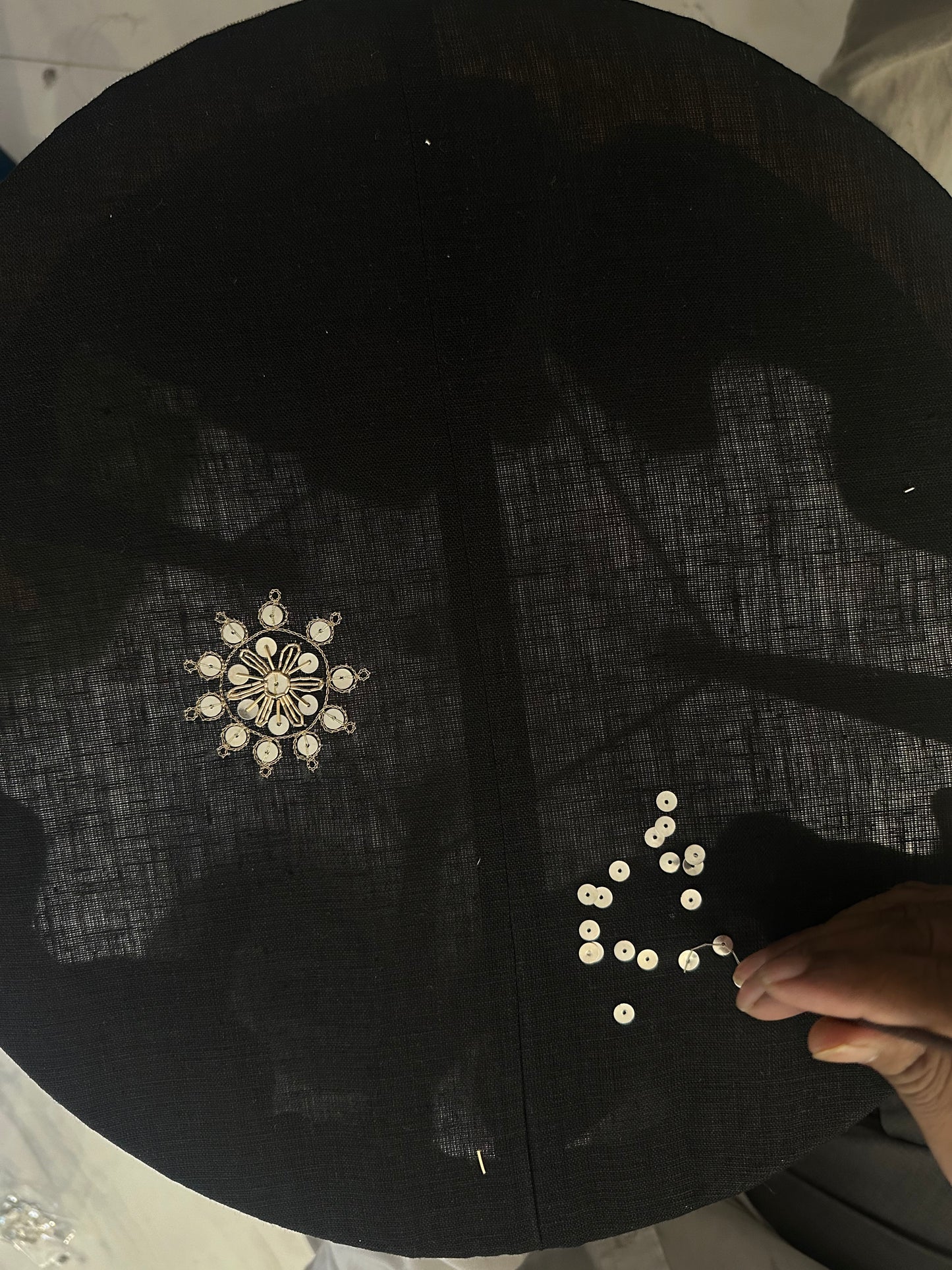 Artisan doing zardozi work on black linen cloth