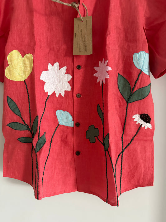 Close up of the patchwork of flowers on a red linen shirt