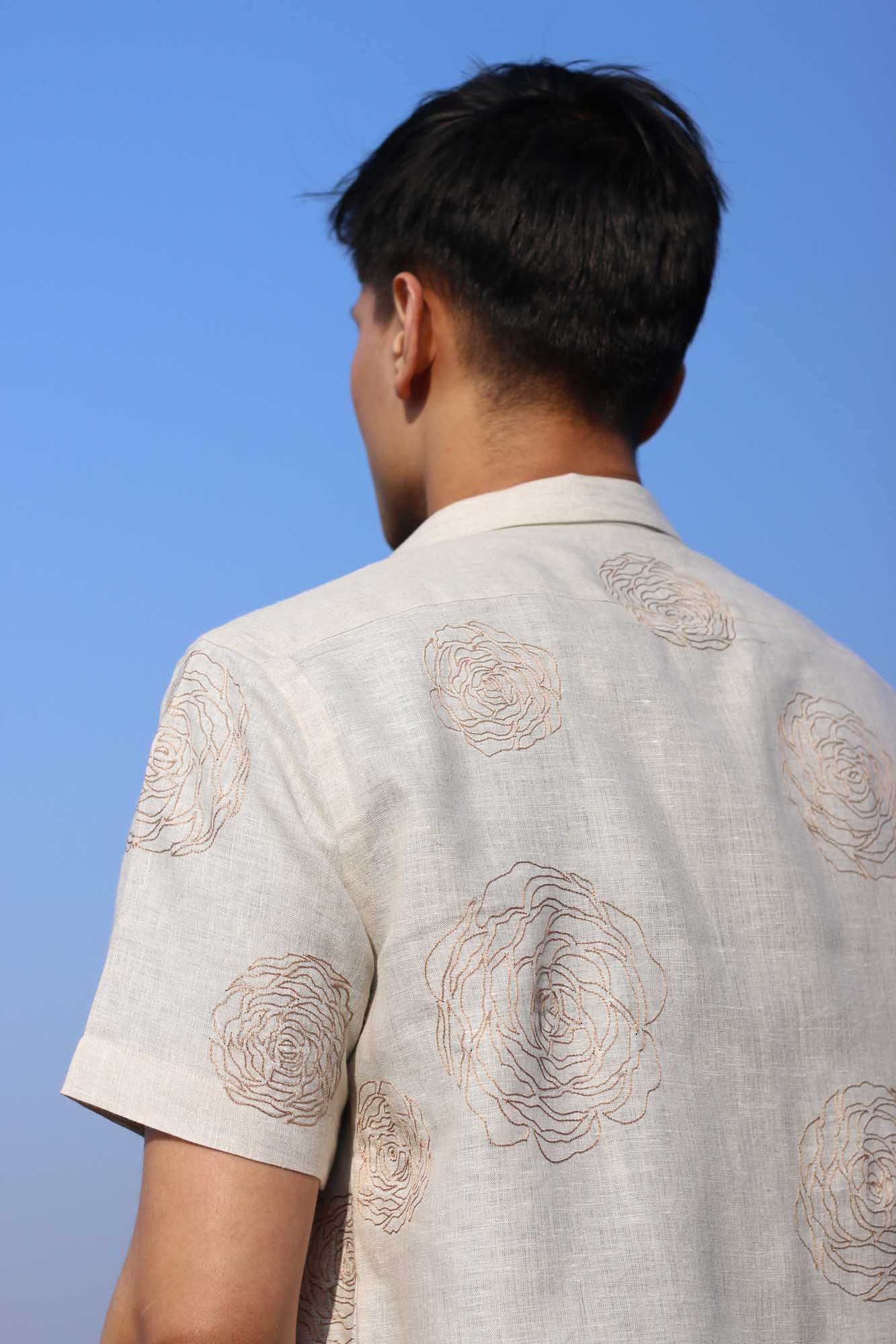 Back of a beige half-sleeve linen shirt with hand-embroidered roses in muted light brown color