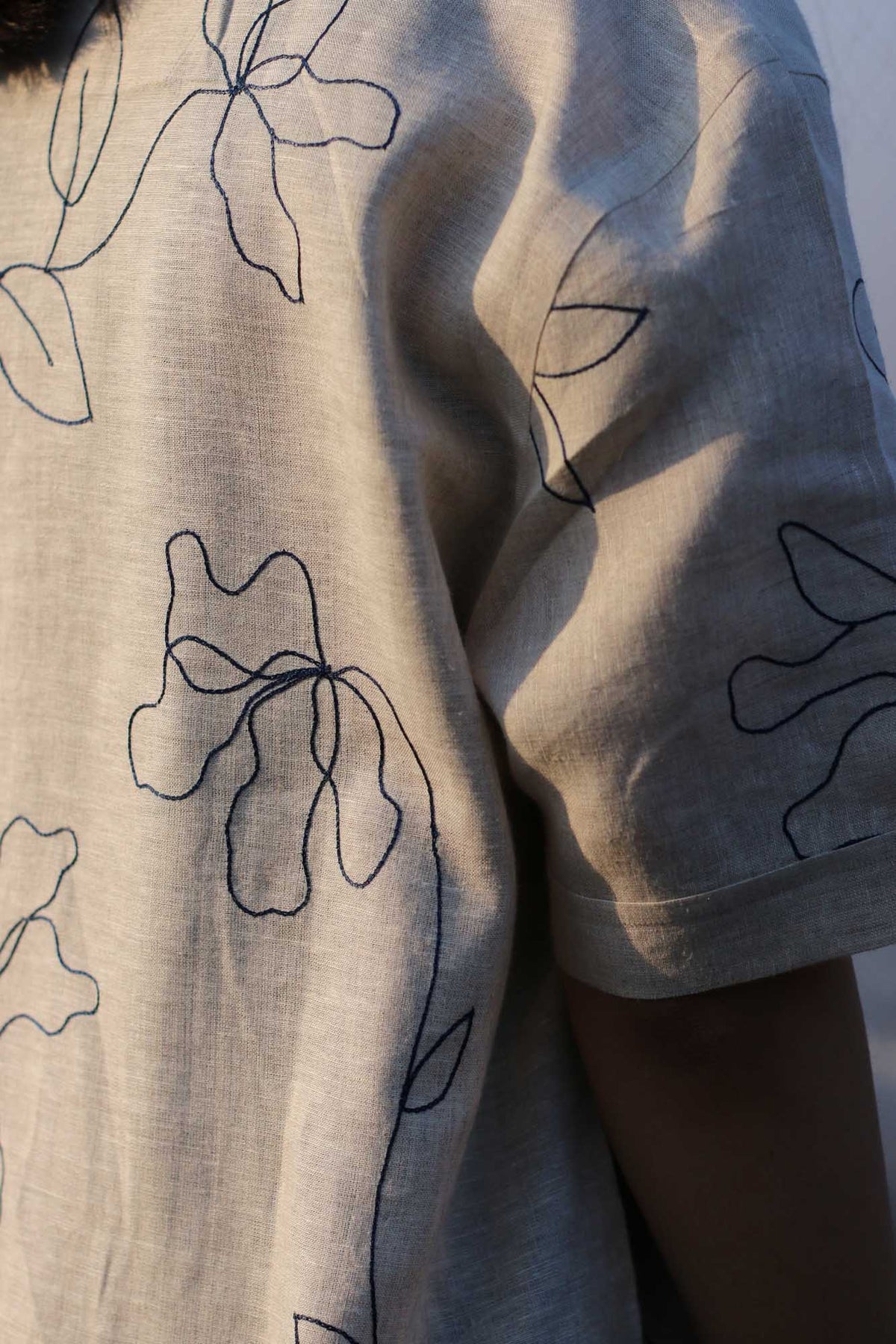 Back view of a beige hand-embroidered floral linen shirt