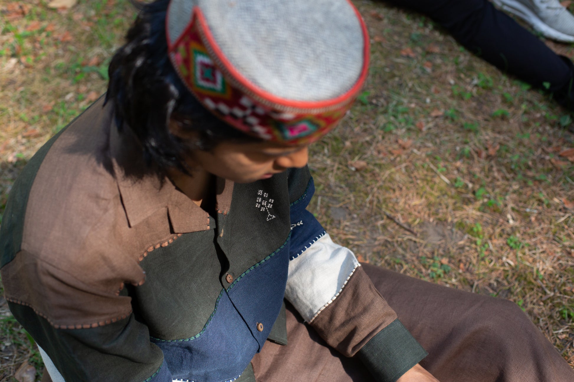 Model wearing an embroidered linen shirt outdoors on grass