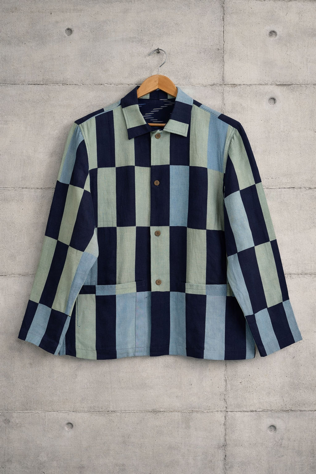 Patchwork checkered linen shirt with dark blue, light green, and light blue pattern displayed against a wall