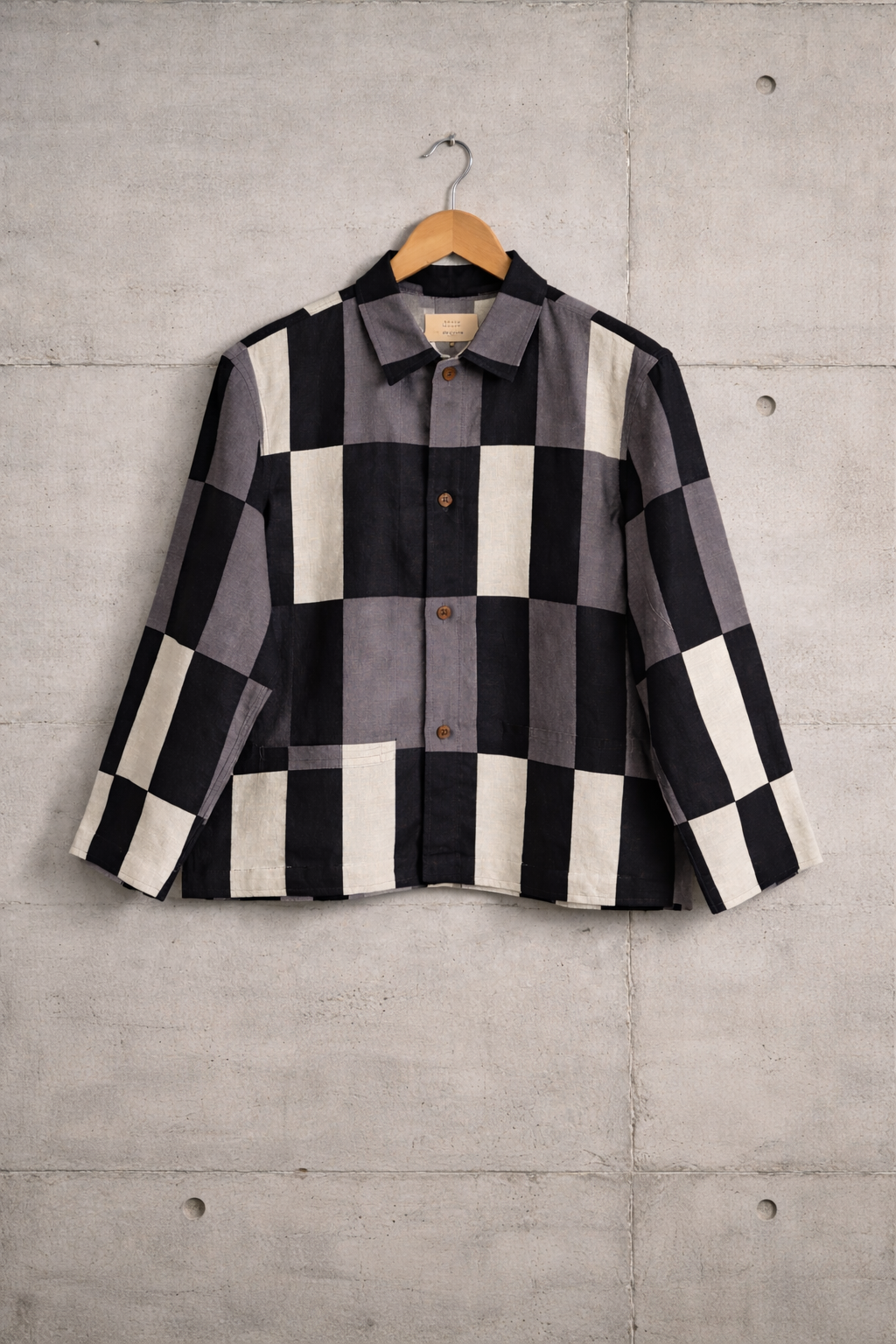 Patchwork checkered linen shirt with grey, white and black pattern displayed against a wall
