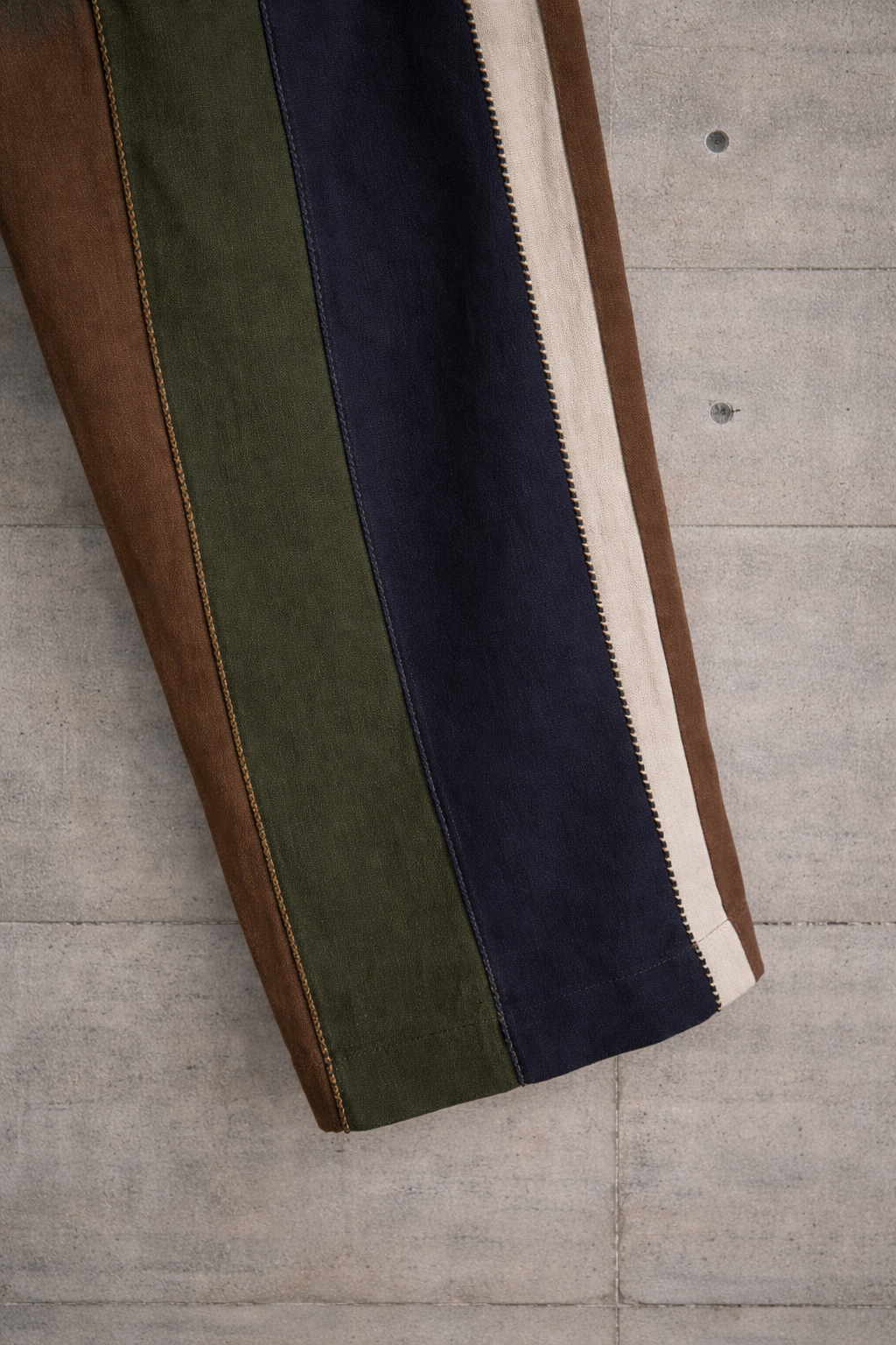 Close up of hem of the color-blocked linen pants displayed against a wall