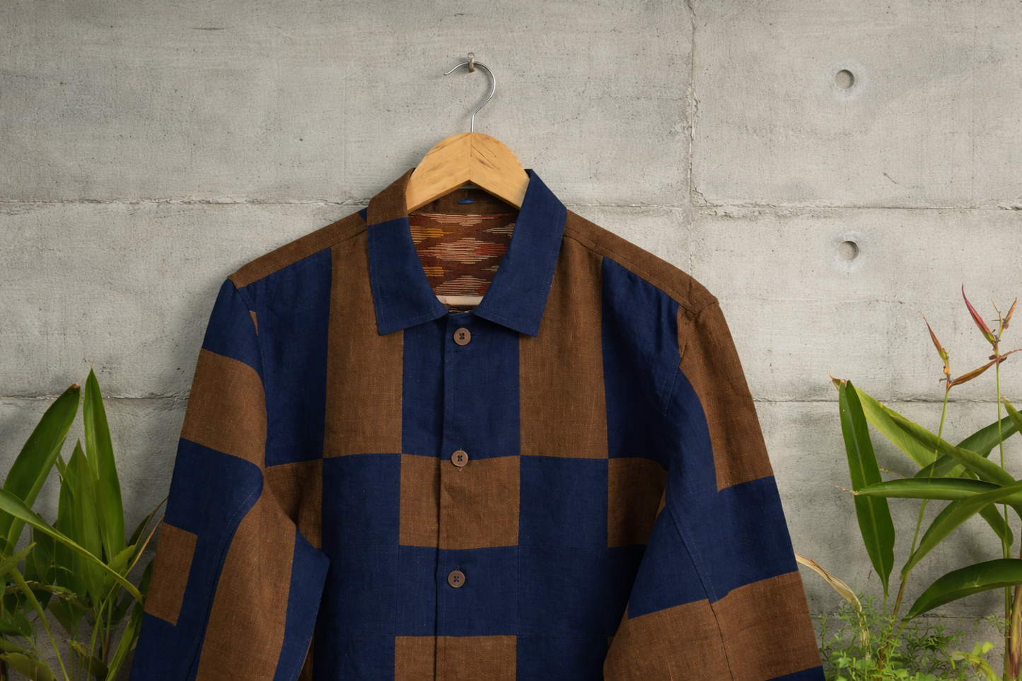 Patchwork checkered linen shirt with blue and brown pattern and ikkat lining displayed against a wall