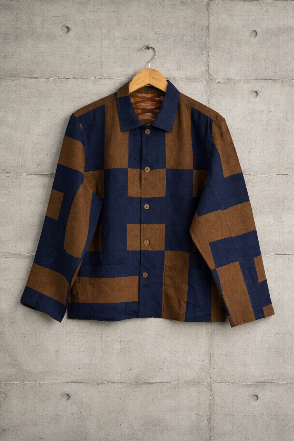Patchwork checkered linen shirt with blue and brown pattern and ikkat lining displayed against a wall