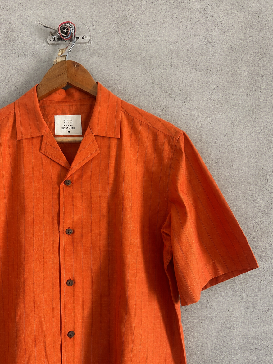 Orange shirt on a hanger against a gray wall