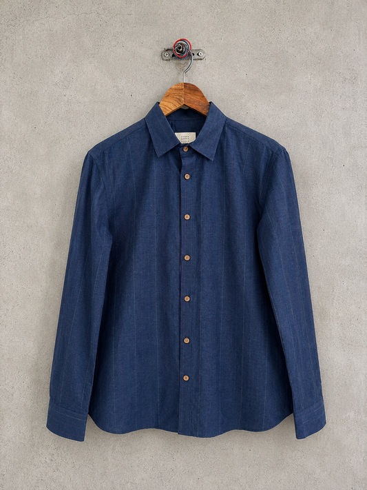 Blue shirt on a wooden hanger against a concrete wall