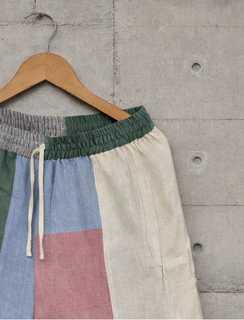 Patchwork linen short closeup displayed against a wall