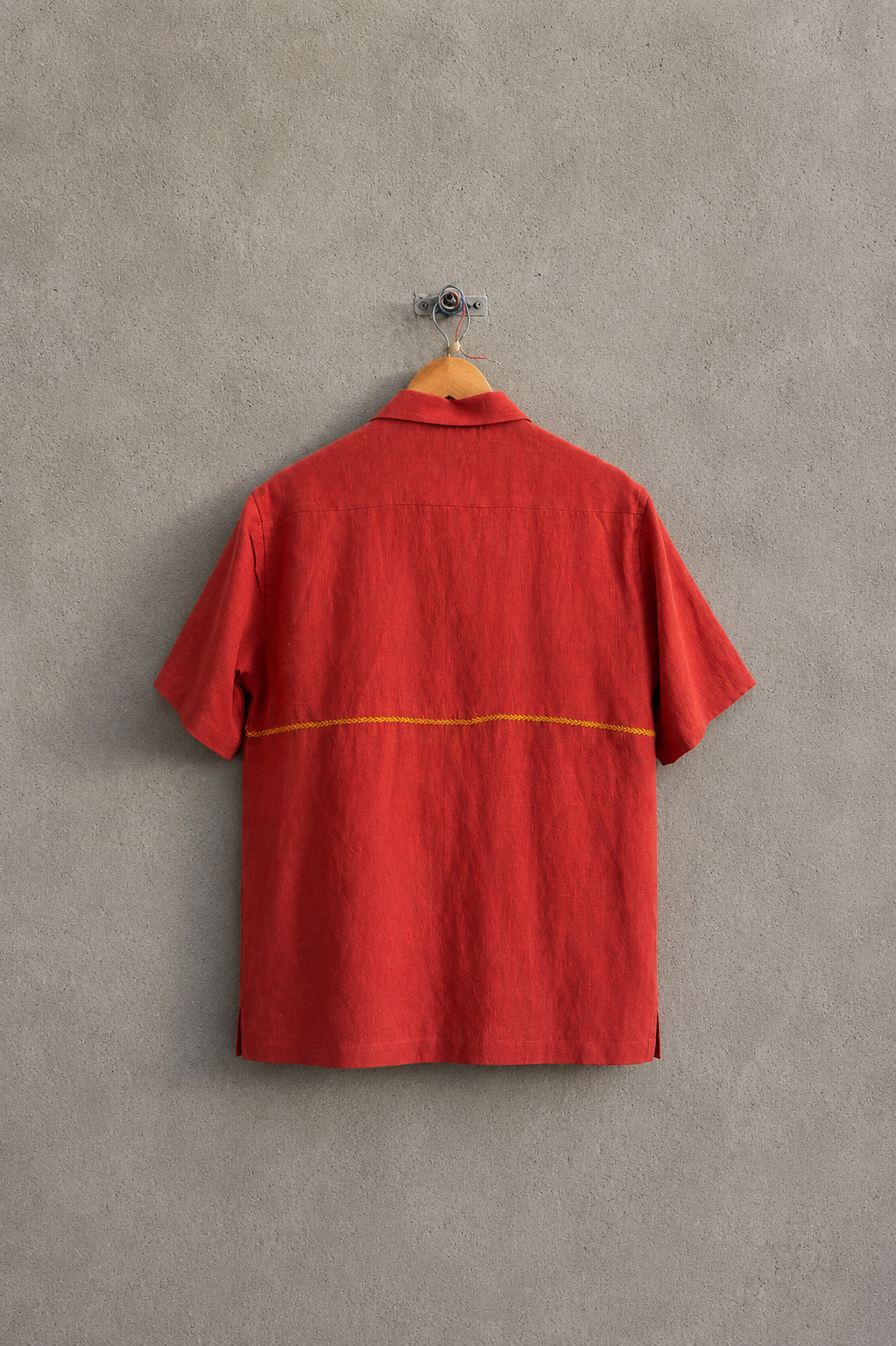 Red shirt on a hanger against a gray wall