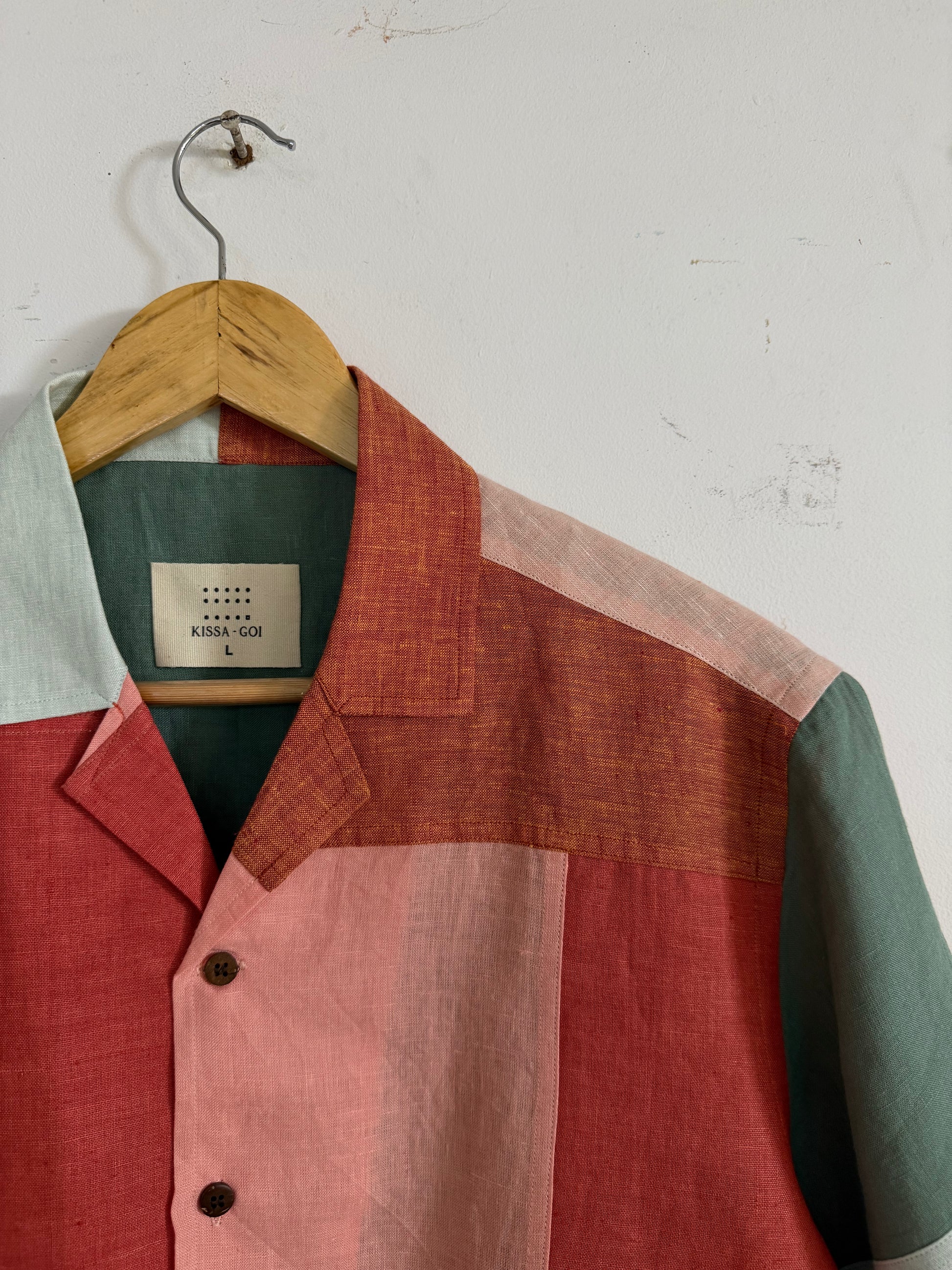 Closeup of patchwork linen shirt displayed against a white wall