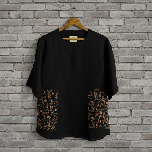 Floral embroidery on black pashmina tshirt displayed against grey brick wall 