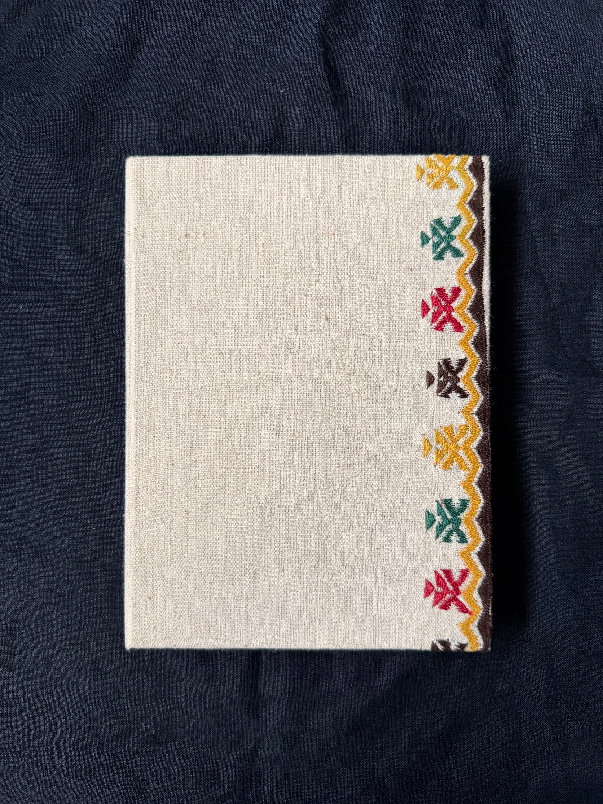 Along the Edge suf embroidered diary placed against a dark surface