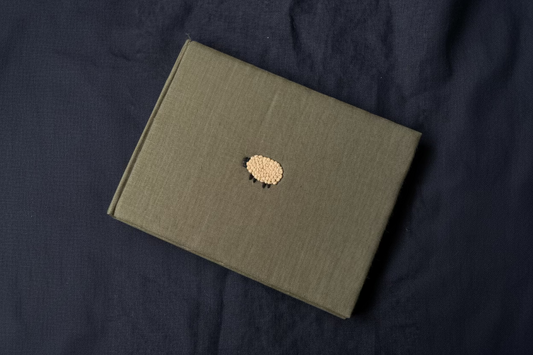 Olive green sheep sketchbook displayed against dark background