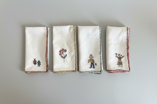 Set of four embroidered napkins on a white surface