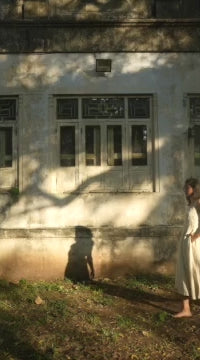 Mariya walking in an off-white ankle-length linen dress with vertical panels